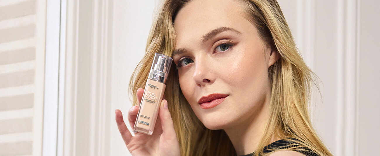 Kobieta trzymająca podkład L'Oréal True Match o odcieniu idealnie dopasowanym do jej odcienia skóry